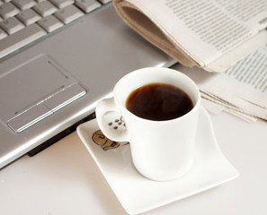 Coffee cup with laptop, glasses and newspaper