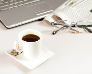 Coffee cup with laptop, glasses and newspaper