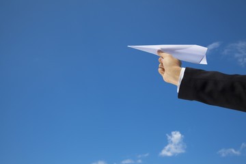 Businessman letting an airplane made of paper fly