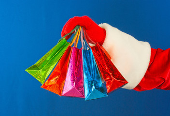 Santa's hand holding colorful bags