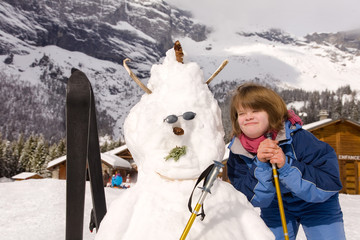 A girl with Down Syndrome and her snowman.