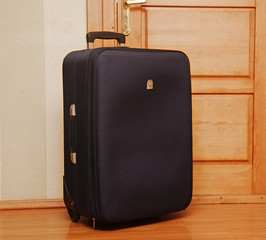 One black suitcase sitting on the entrance inside the front door