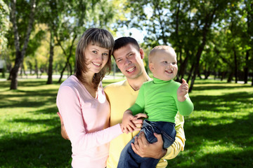 Fototapeta na wymiar Young family with a child in summer park