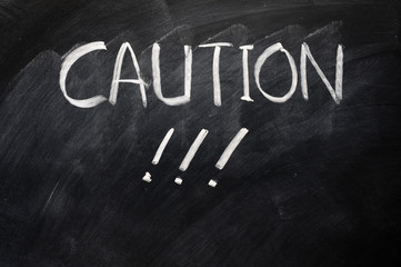 Caution written on blackboard