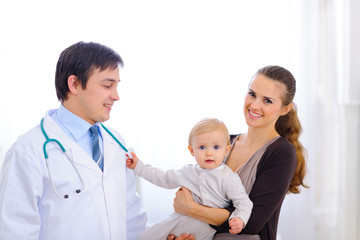 Baby on mothers hand touching stethoscope of pediatric doctor