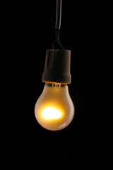 A lit light bulb on black background