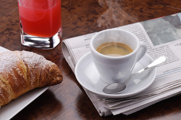 Caffè caldo con croissant, succo di frutta e giornale