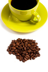 closeup shot of delicious coffee grains and green mug filled wit