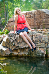 portrait of a young girl in red smiling and sitting on the rocks