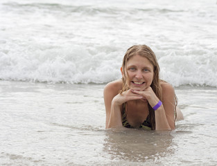 Portrait of young woman lying in water on beach