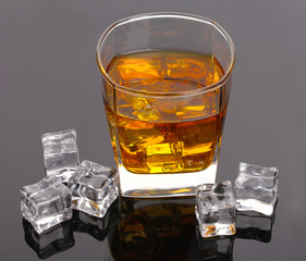 glass of scotch whiskey and ice on grey table