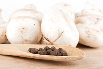 Fresh mushrooms with spoon of pepper