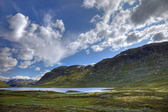 Picturesque norwegian landscape with small lake and green hills,