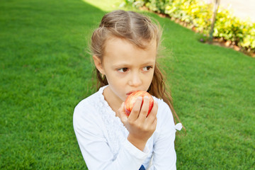 Девочка ест красное яблоко