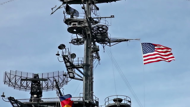 USA flag and antennas on carrier control tower in blue sky
