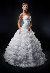 Fototapeta premium Pretty bride in white nuptial dress posing in studio
