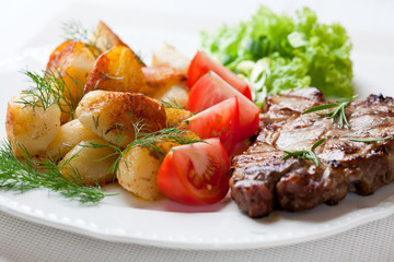 Grilled pork steak with oven baked potatoes and salad
