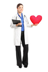 Full length portrait of a female doctor holding a red heart