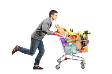 Young man running and pushing a shopping cart full with food © Ljupco Smokovski