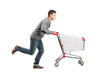 Young man running and pushing an empty shopping cart