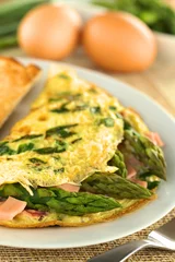Foto auf Leinwand Green asparagus and ham omelet with eggs in the back © Ildi