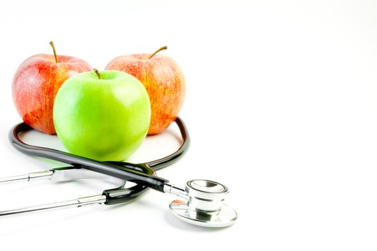 medical stethoscope and three apples