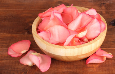 beautiful pink rose petals in wooden bowl on table