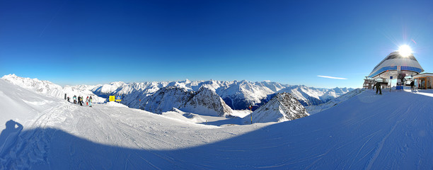 Panorama with ski trail, tall snow drifts on the slope of Tyrolean Alps and blue sky, hovering...