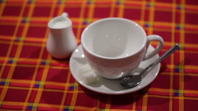 Flowing tea in a cup with a saucer, toasts, sugar and milk jug