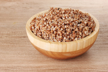 Boiled buckwheat in a wooden bowl on wooden background
