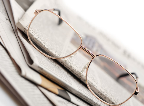 Eyeglasses lie on a pile of newspapers
