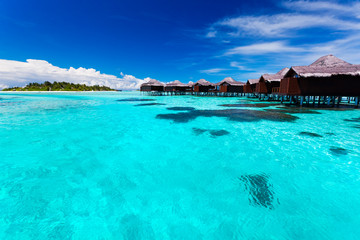 Overwater bungallows in blue tropical lagoon