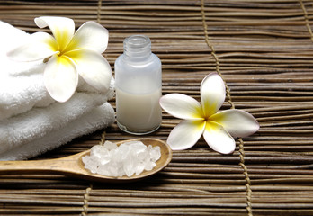 Fototapeta na wymiar herbal salt in spoon with frangipani on towel and massage oil