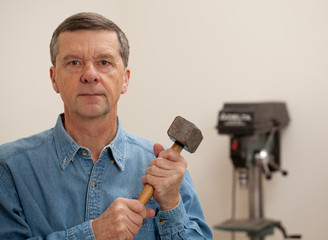 Senior man holding a large hammer