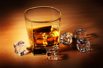 glass of scotch whiskey and ice on wooden table