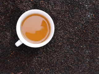 Tè nella tazza su fondo di tè in foglie