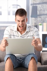 Young man shouting at laptop screen