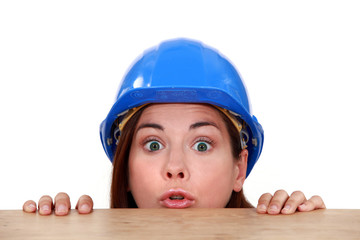 Female builder peering over ledge