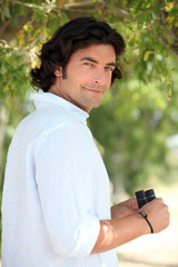 Smiling man with a pair of binoculars in the countryside