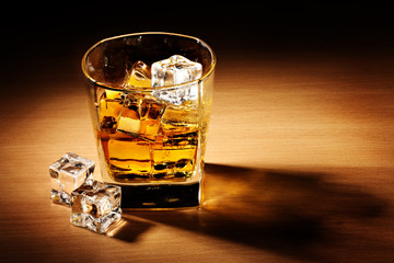 glass of scotch whiskey and ice on wooden table