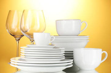 Fototapeta premium empty bowls, plates, cups and glasses on yellow background