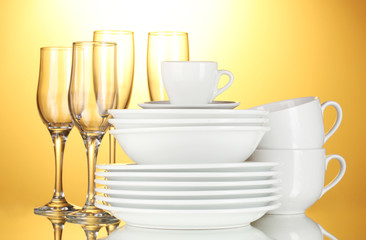 empty bowls, plates, cups and glasses on yellow background