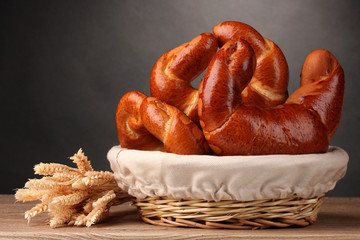 Baked bread in basket on wooden table on grey background