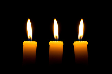 Three candles with flame over black background