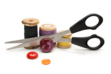Thread bobbin, scissors and buttons on white