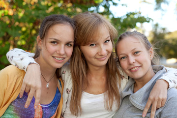 Portrait of three pretty student girls in the park