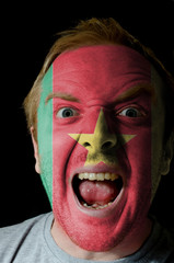 Face of crazy angry man painted in colors of Cameroon flag