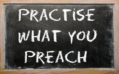 Proverb "Practise what you preach" written on a blackboard