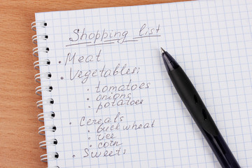Shoping list and pen on wooden table