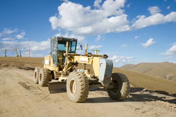 Obraz premium Road building machine with highland landscape